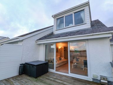 A terrace with black outdoor furniture and sliding glass doors leading to a living room with sofas at White Sails in Y Felinheli