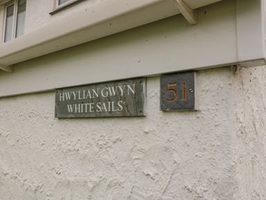 A house wall with signs reading Hwylian Gwyn White Sails and number 51 at White Sails in Y Felinheli