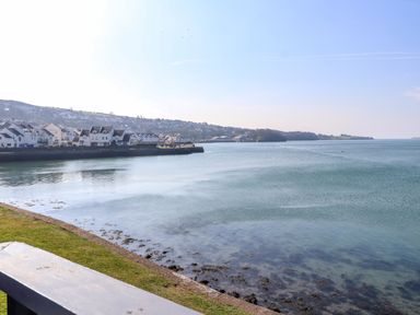 A view of water with houses on the shore and hills in the background at White Sails in Y Felinheli