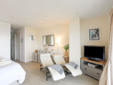A sitting area with two lounge chairs and a television on a stand in a room at White Sails in Y Felinheli
