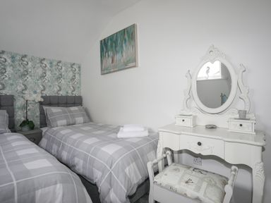 A bedroom with two single beds and a white dressing table with mirror at White Sails in Y Felinheli
