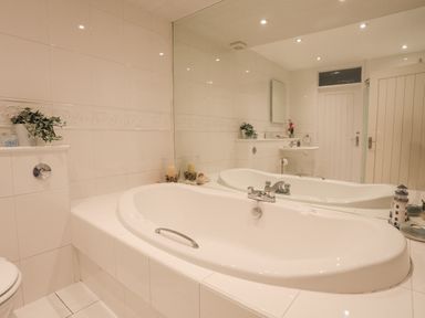 A bathroom with a white bathtub sink toilet and mirror at White Sails in Y Felinheli