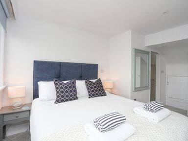 A bedroom with a double bed pillows bedside tables lamps and towels at White Sails in Y Felinheli