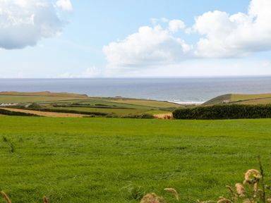 A landscape with green fields and hedges overlooking the sea at Northcott Hut Stibb near Bude