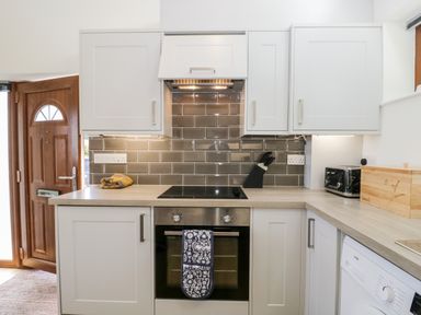 A kitchen with stove oven countertop knife block toaster bread box and washing machine at Little Barn in Grange-Over-Sands near Cartmel