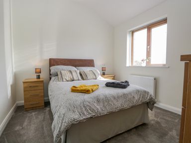 A bedroom with a double bed two bedside tables with lamps and a window at Little Barn in Grange-Over-Sands near Cartmel