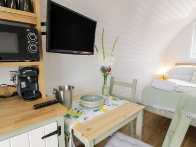 A small dining area with a table and chairs a vase with flowers a microwave and coffee maker a bed with folded towels in Laird Lodge 1 Lochmaben