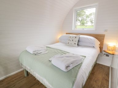 A bedroom with a bed towel robes slippers and a window showing trees at Laird Lodge 1 in Lochmaben