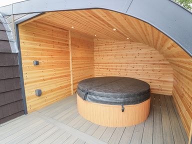 An outdoor covered wooden space with a round hot tub at Laird Lodge 1 in Lochmaben