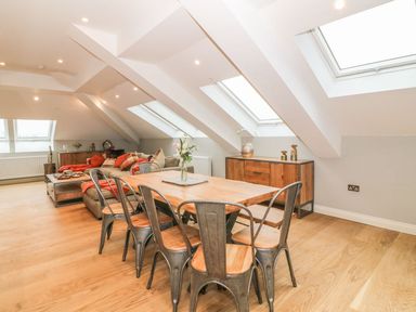 A dining table with six metal chairs and a wooden cabinet under skylights in a living space at Sardis Chapel 1 in Malltraeth