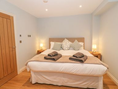 A bedroom with a double bed two bedside tables lamps and folded towels at Sardis Chapel 1 in Malltraeth