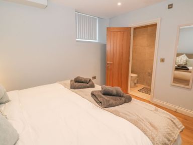 A bedroom with a bed and folded towels at the foot of the bed and an open door leading to a bathroom at Sardis Chapel 1 in Malltraeth