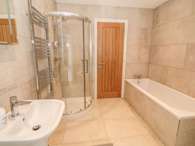 A bathroom with a bathtub shower enclosure sink and wooden door at Sardis Chapel 1 Malltraeth