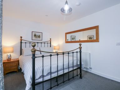 A bedroom with a metal bed frame two bedside tables with lamps a large wall mirror and framed pictures at Escape To The Chapel Anglesey in Bryngwran near Rhosneigr