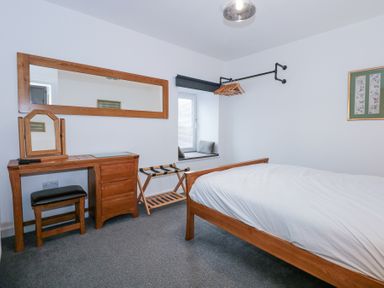 A bedroom with a wooden bed a dressing table and a wall-mounted clothes rack at Escape To The Chapel Anglesey Bryngwran near Rhosneigr