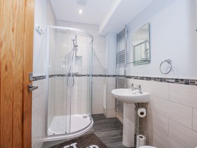 A bathroom with a curved glass shower enclosure sink mirror and towel rack at Escape To The Chapel Anglesey Bryngwran near Rhosneigr