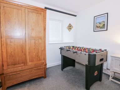 A room with a wooden wardrobe a foosball table a window and framed picture at Escape To The Chapel Anglesey Bryngwran near Rhosneigr