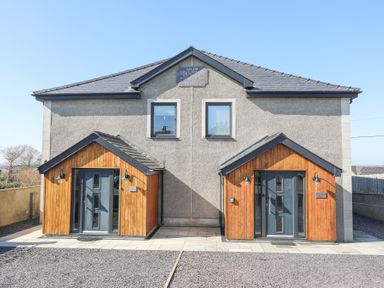 A modern duplex house with two blue front doors and wooden porch coverings at Escape To The Chapel Anglesey Bryngwran near Rhosneigr