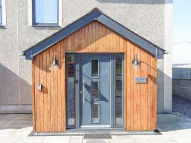 A front door with windows and lights on a wooden porch at Escape To The Chapel Anglesey Bryngwran near Rhosneigr
