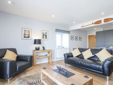 A living room with black leather sofas yellow cushions wooden coffee table and wooden side table at Escape To The Chapel Anglesey Bryngwran near Rhosneigr