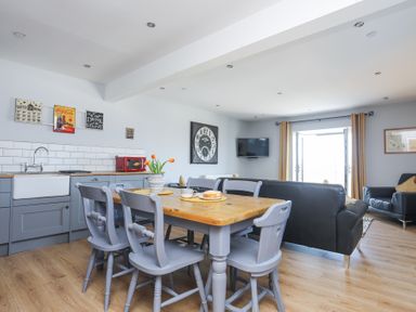 A kitchen and living room with a wooden dining table and gray chairs at Escape To The Chapel Anglesey Bryngwran near Rhosneigr