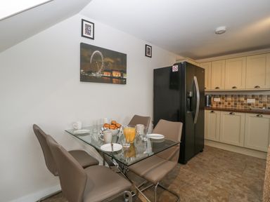 A kitchen with a glass dining table and brown chairs next to a black refrigerator at Top Lodge in Llanvair-Discoed near Penhow