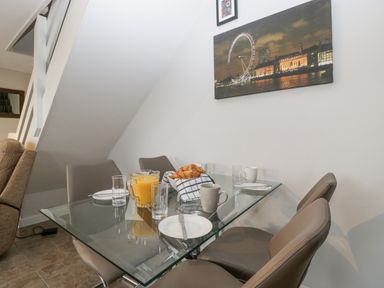 A dining area with a glass table set with plates mugs glasses orange juice and croissants at Top Lodge Llanvair-Discoed near Penhow