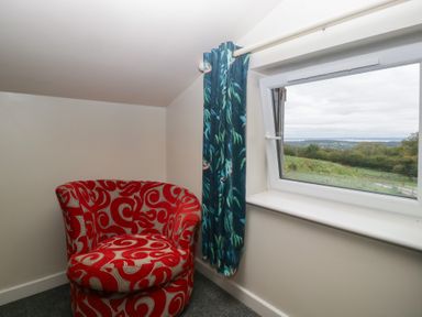 A chair and window in a snug room at Top Lodge Llanvair-Discoed near Penhow