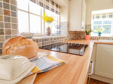 A kitchen countertop with a loaf of bread a butter dish and a cooktop at The Old Post Office in Llanelian near Old Colwyn