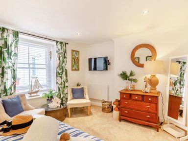 A sitting area with armchairs plants and a wooden dresser with a lamp and mirror at Pentreath in Kingsand