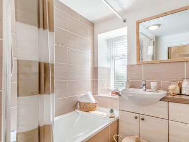 A bathroom with a bathtub shower curtain and sink with a mirror above it at Pentreath in Kingsand