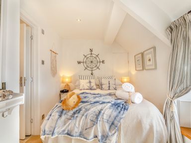 A bedroom with a bed with pillows and blankets and a compass wall decoration at Pentreath in Kingsand