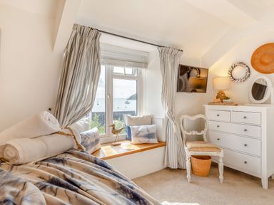 A bedroom with bed towels window seat and chest of drawers at Pentreath in Kingsand