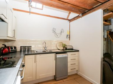A kitchen with a sink toaster kettle and dishwasher at Nympy Cottage in Nympsfield near Nailsworth