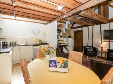 A kitchen and living area with a dining table and flower vase at Nympy Cottage Nympsfield near Nailsworth