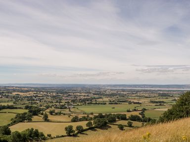 A countryside landscape with fields trees and distant hills at Nympy Cottage in Nympsfield near Nailsworth