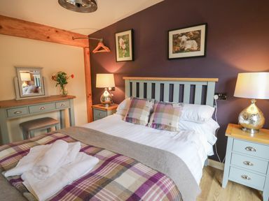 A bedroom with a bed and bedside tables with lamps and a dressing table with a mirror at Daffodil in Llangadfan
