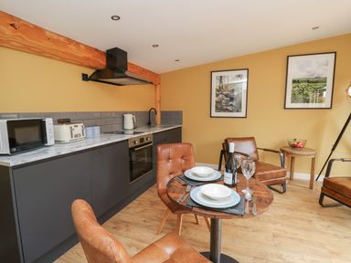 A kitchen and dining area with a wooden table set for two and leather chairs at Rhosyn in Llangadfan