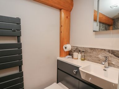 A bathroom sink with a mirror above and a dark towel radiator at Rhosyn in Llangadfan
