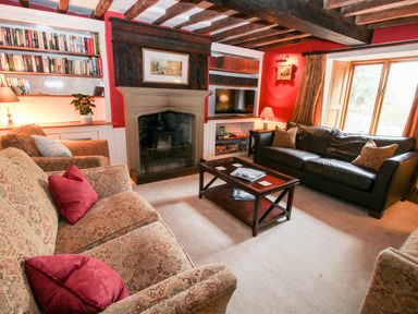 A sitting room with patterned sofas a leather couch a coffee table fireplace and bookshelves at Pentre Hall Bronygarth near Chirk