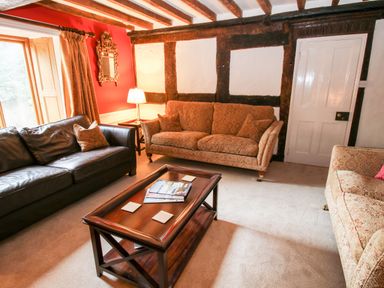A living room with patterned sofas a leather sofa a wooden coffee table and a lamp at Pentre Hall in Bronygarth near Chirk