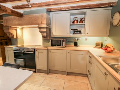 A kitchen with wooden beams a double oven microwave cabinets and a bowl of fruit at Pentre Hall Bronygarth near Chirk