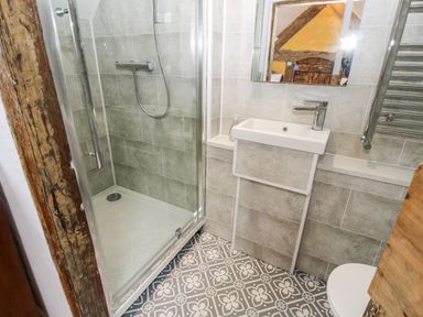 A bathroom with a walk-in shower sink mirror and patterned tile floor at Pentre Hall in Bronygarth near Chirk