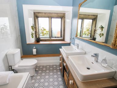 A bathroom with two sinks a toilet a bathtub and a window with a plant on the sill at Pentre Hall in Bronygarth near Chirk