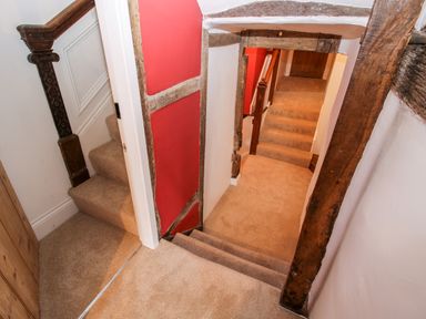 A hallway with beige carpeted stairs and wooden beams on walls at Pentre Hall in Bronygarth near Chirk