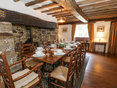 A dining room with a long wooden table set with white dishes and glasses at Pentre Hall in Bronygarth near Chirk