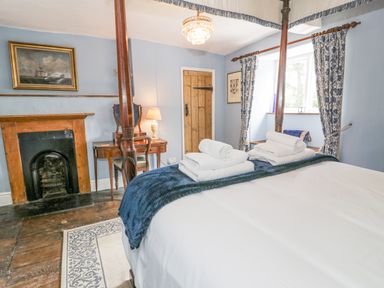 A bedroom with a four-poster bed folded towels on the bed a wooden door and a fireplace at Pentre Hall in Bronygarth near Chirk