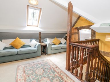 A seating area with two blue sofas and cushions next to a wooden staircase in an attic room at Pentre Hall in Bronygarth near Chirk