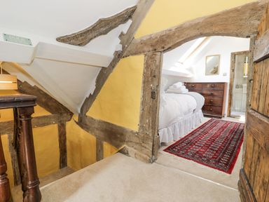 A staircase leading to a bedroom with a bed chest of drawers and a red rug at Pentre Hall Bronygarth near Chirk