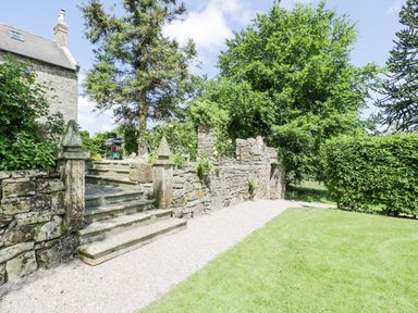 An outdoor stone stairway leading to a garden area with stone walls and greenery at Pentre Hall in Bronygarth near Chirk